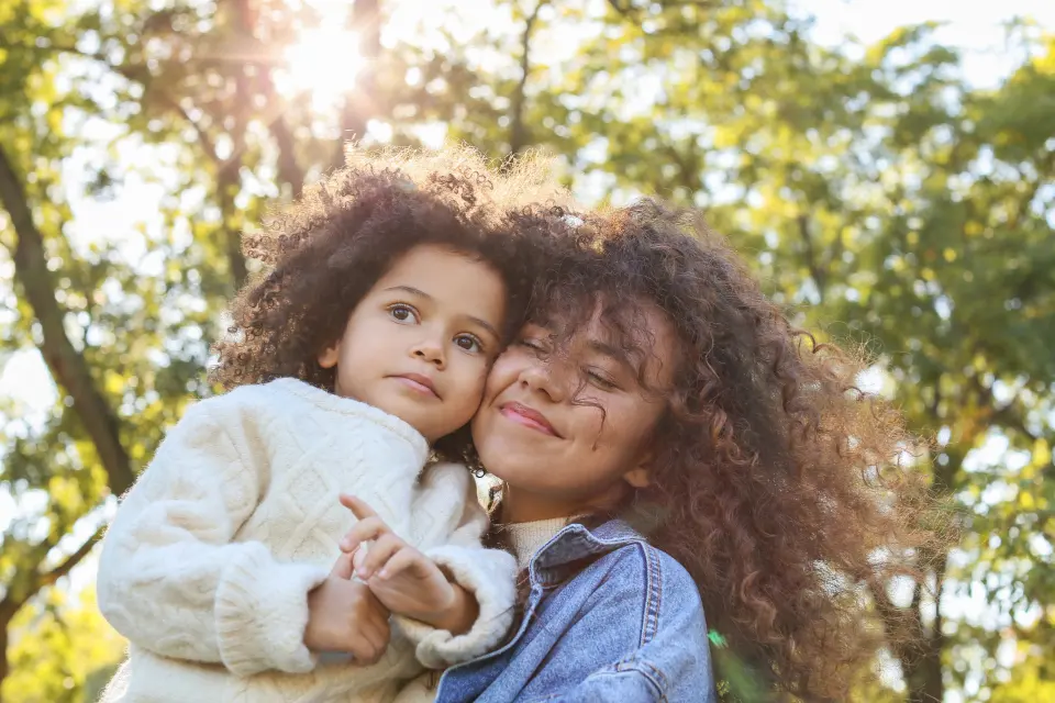 Mãe e filha abraçadas ao ar livre